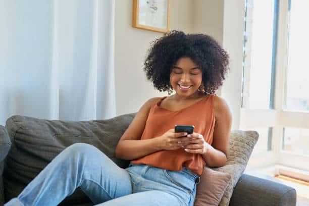 Shot Of A Young Woman Using A Cellphone While Relaxing On A Sofa At Home